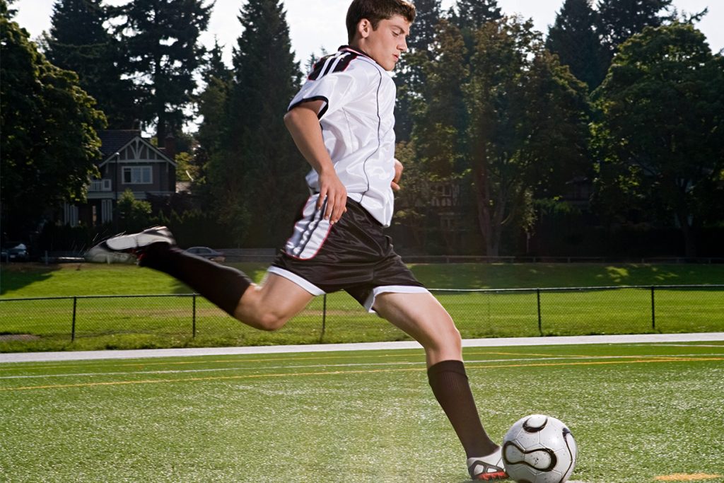Estudiante internacional jugando al fútbol con su equipo en el campus de EE. UU.