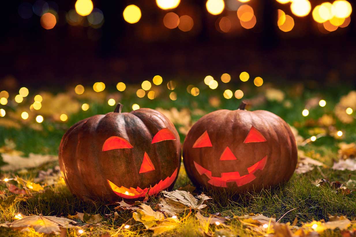 Estudiantes celebrando Halloween estudiando en el extranjero con disfraces y calabazas.